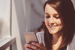 A happy women with a debit card and phone